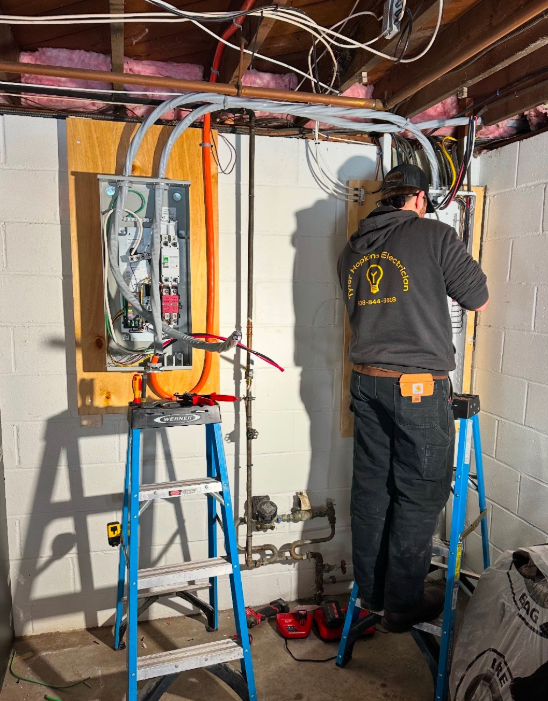 A man standing on a ladder working on an electrical box