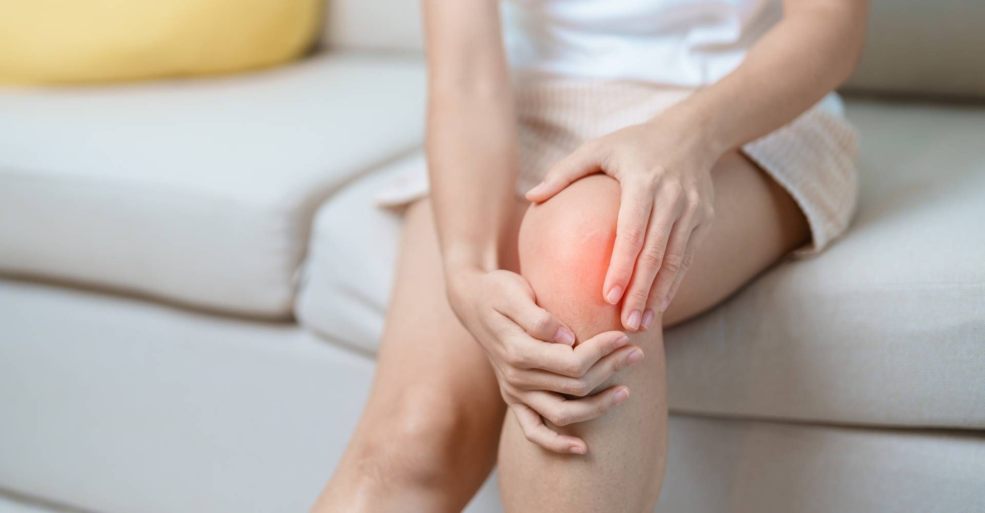 Woman seated, holding her knee, which is red with pain.