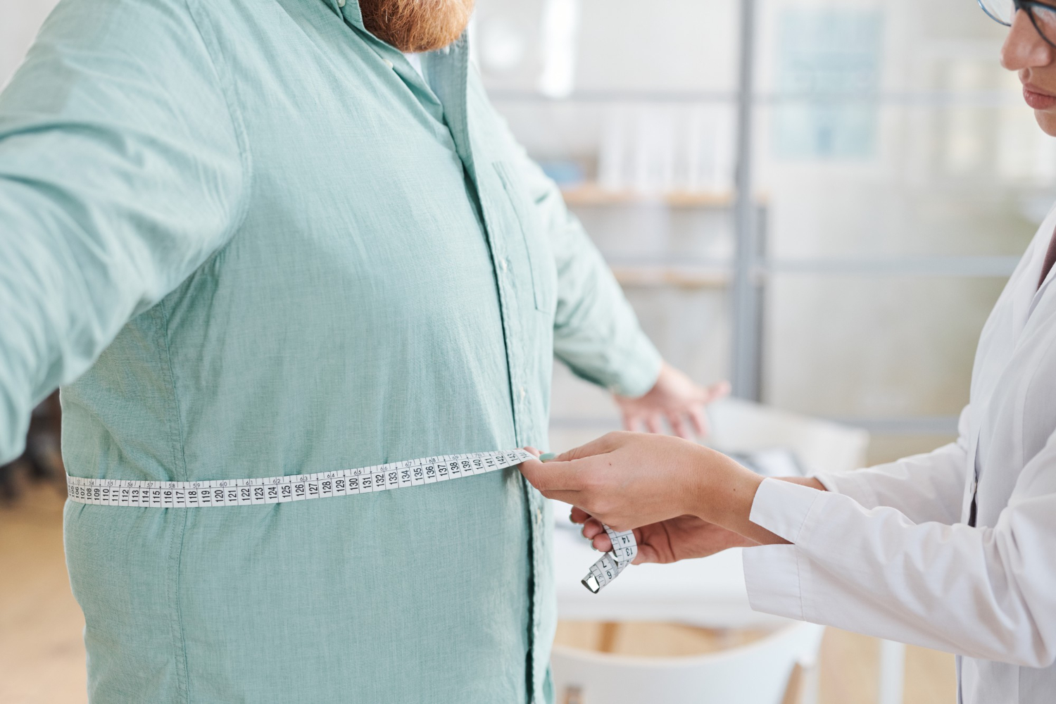 A person's waist being measured by a medical professional.