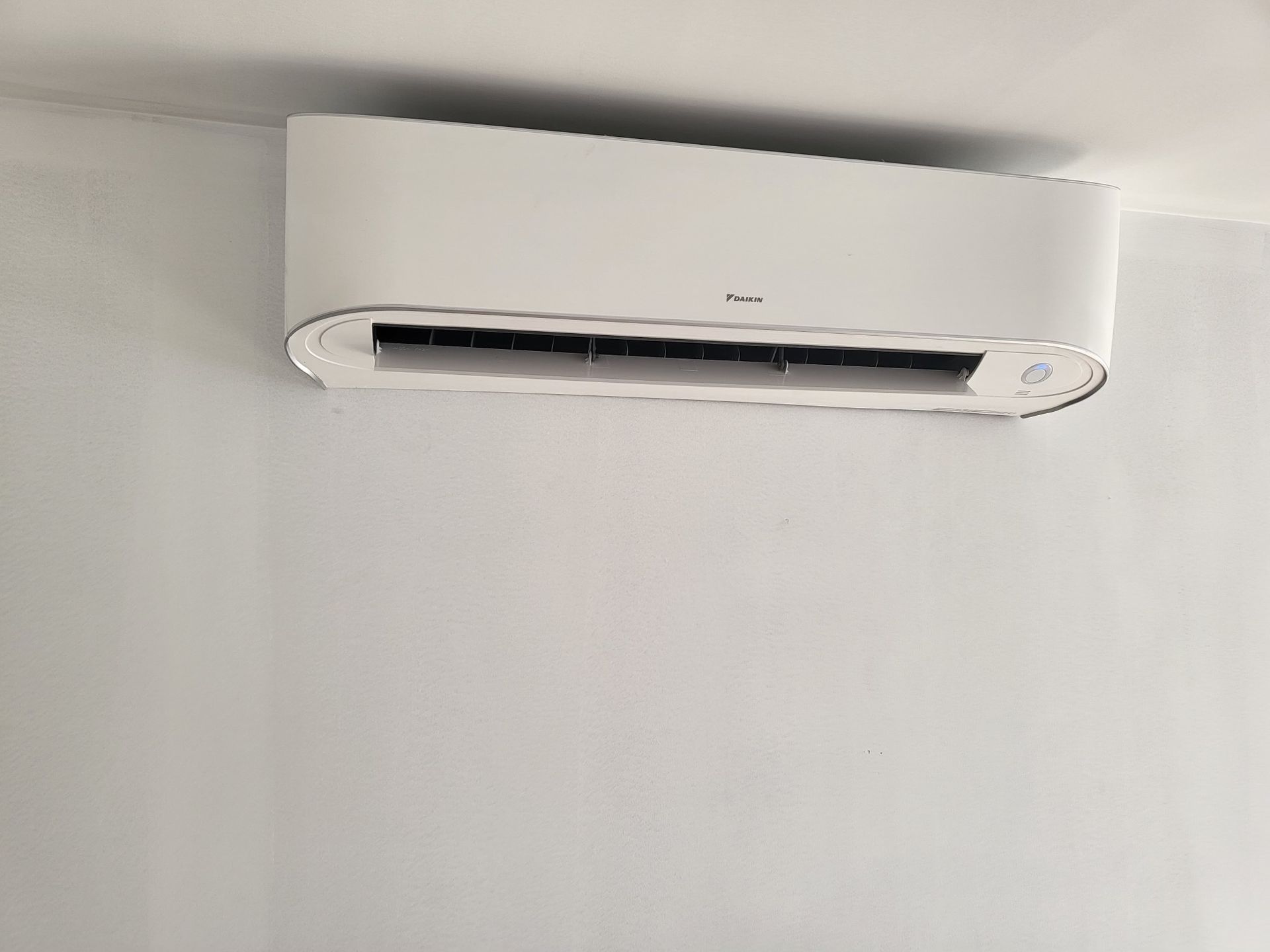 A white air conditioner is hanging from the ceiling in a room.