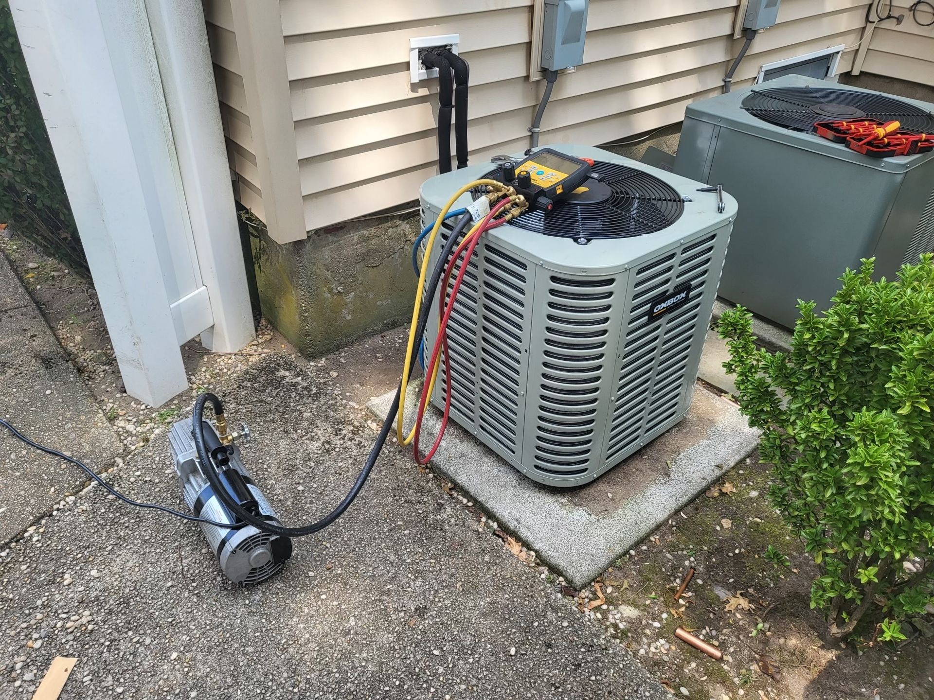 An air conditioner is being serviced outside of a house.