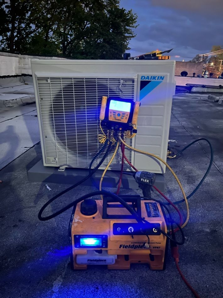 HVAC technician working on a Daikin AC unit on a rooftop, using Fieldpiece equipment. Evening setting, blue and yellow hues.