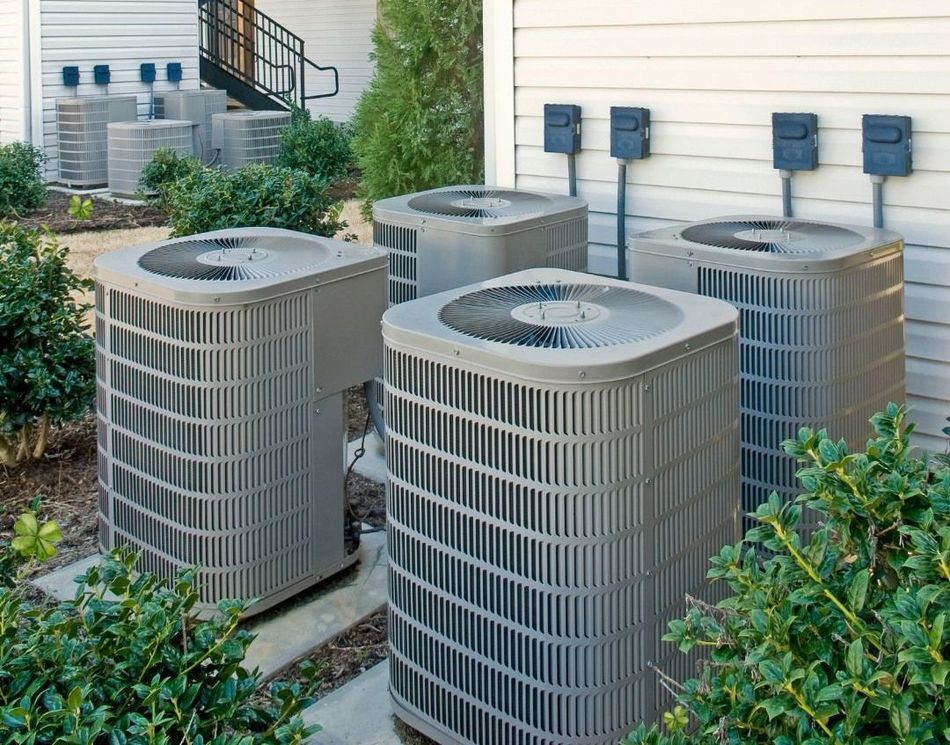 A row of air conditioners are sitting outside of a building.