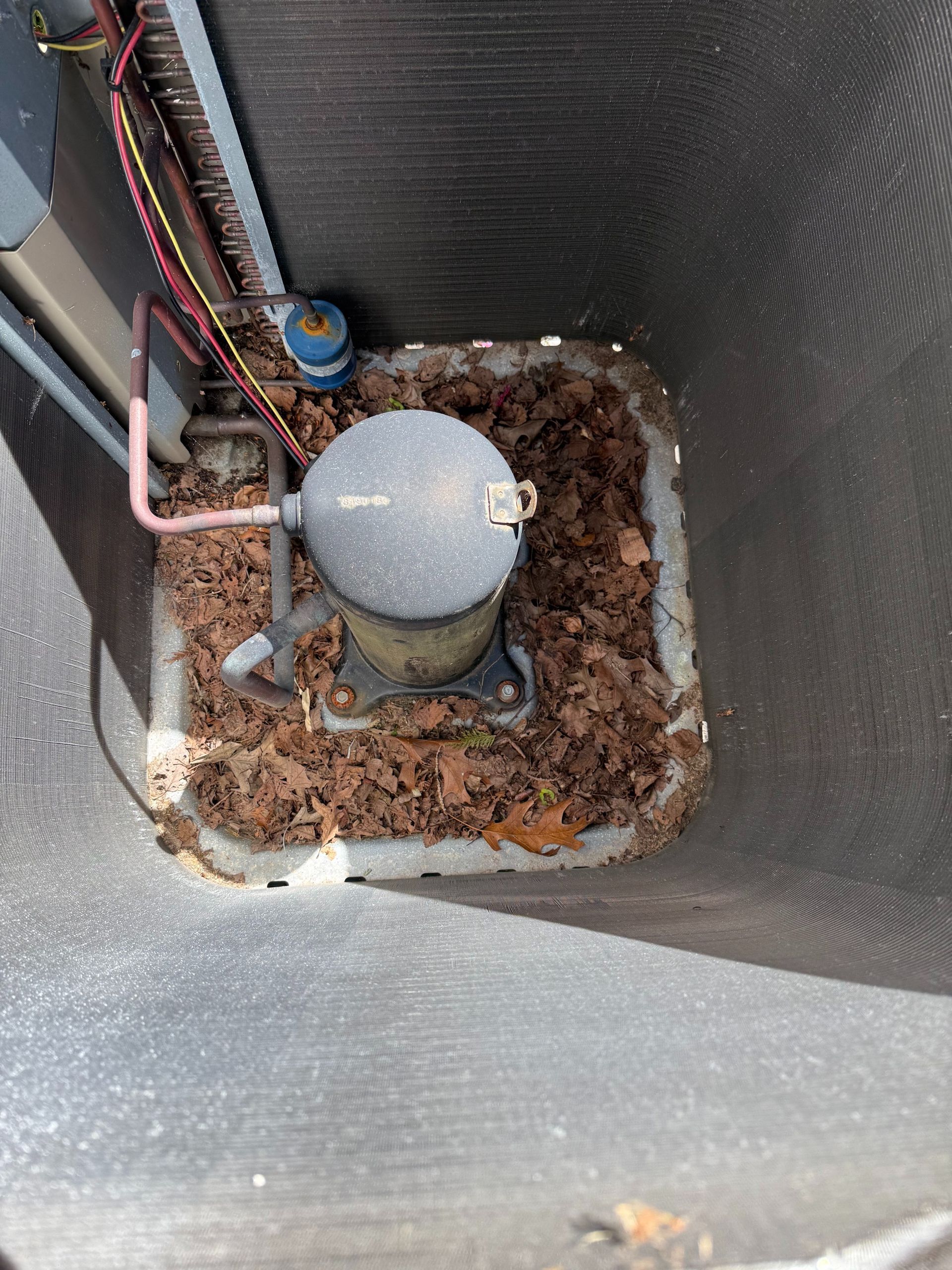 AC unit compressor with debris around its base.