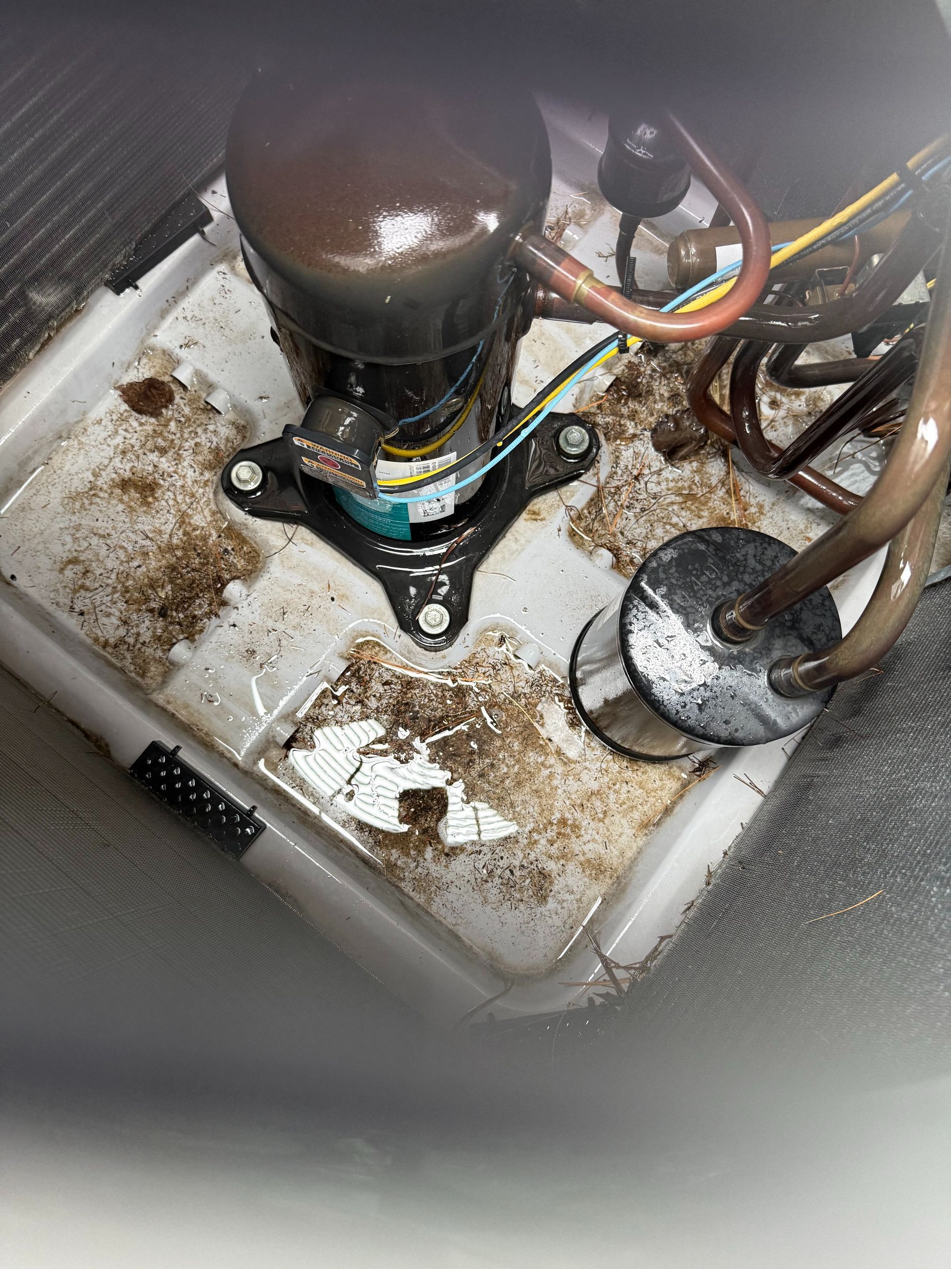 Air conditioner compressor with dirt and wear on a white plastic base.