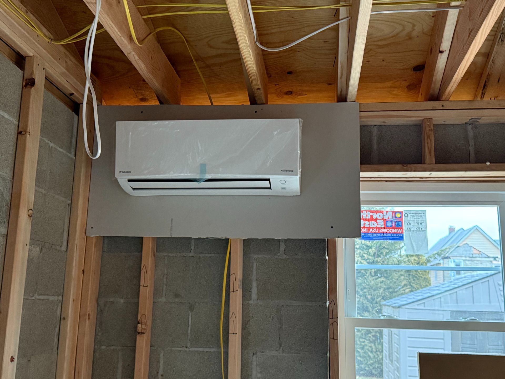 Mini-split air conditioner mounted on drywall, inside a room under construction.