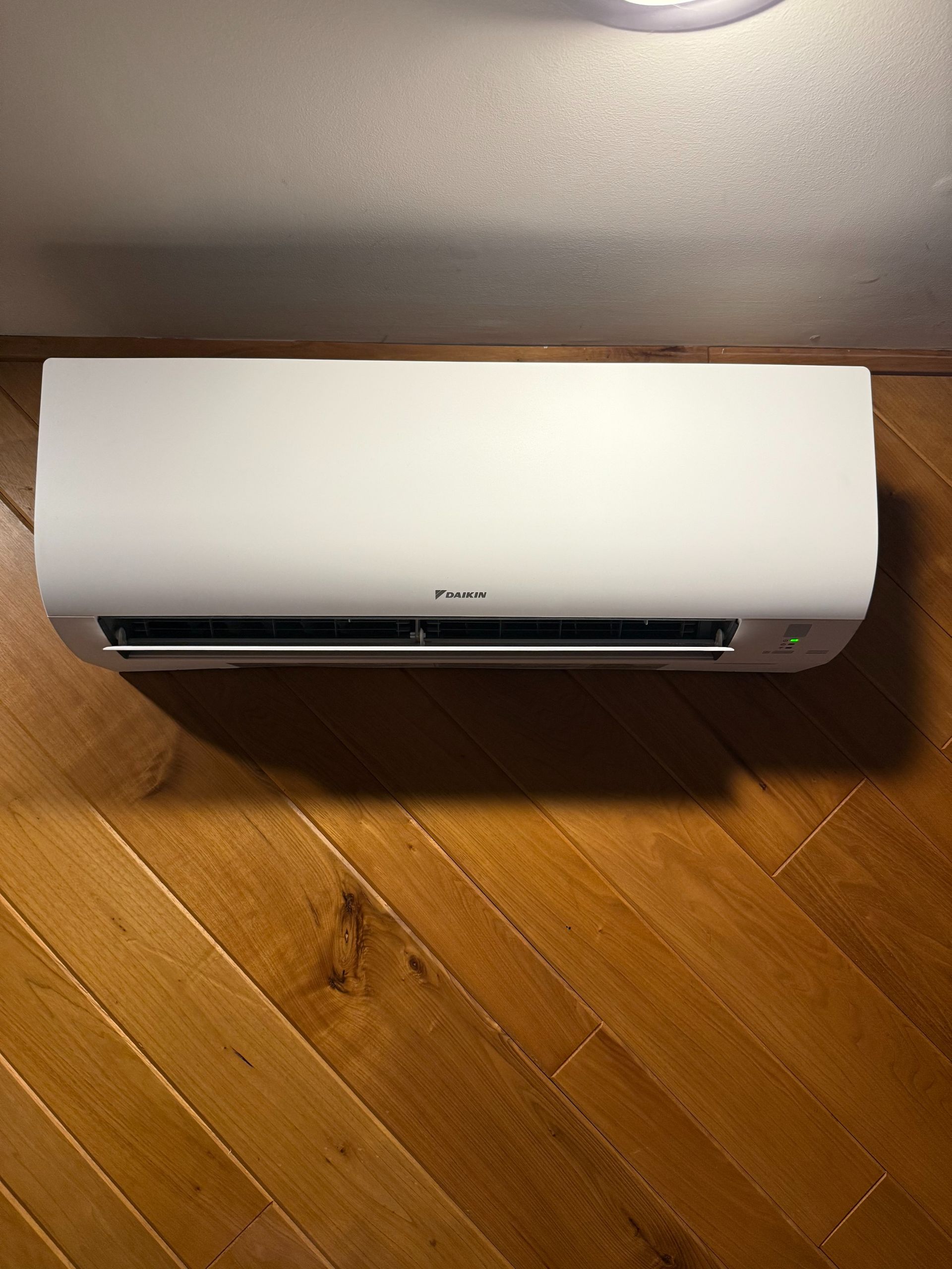 White air conditioner mounted on a wooden wall.