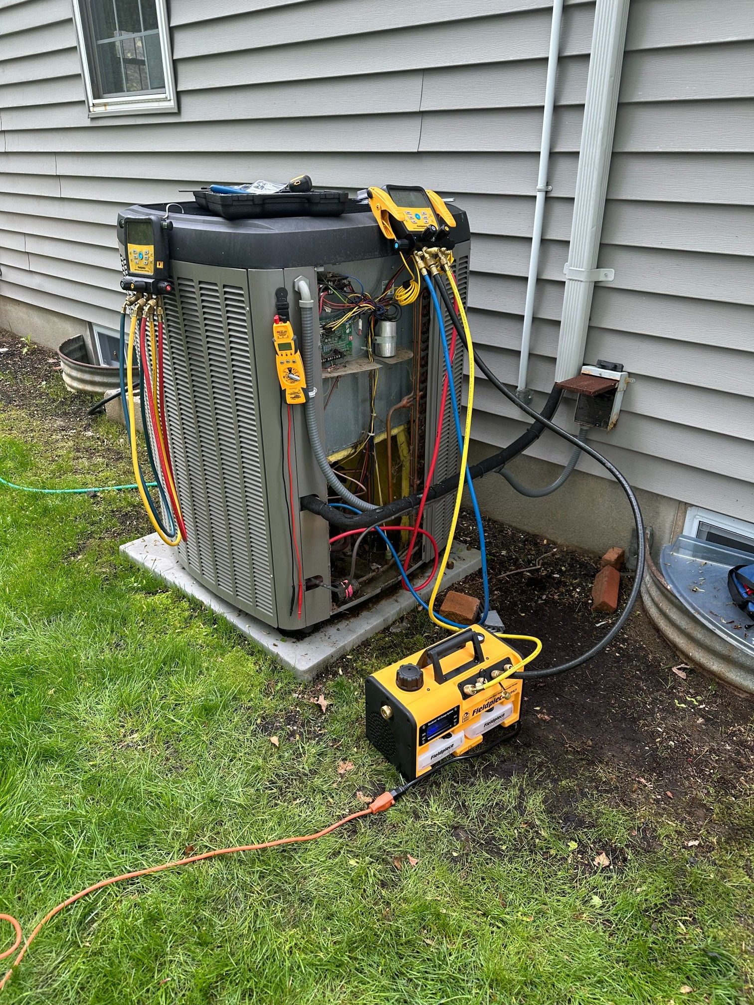 HVAC unit being serviced outdoors with equipment connected.