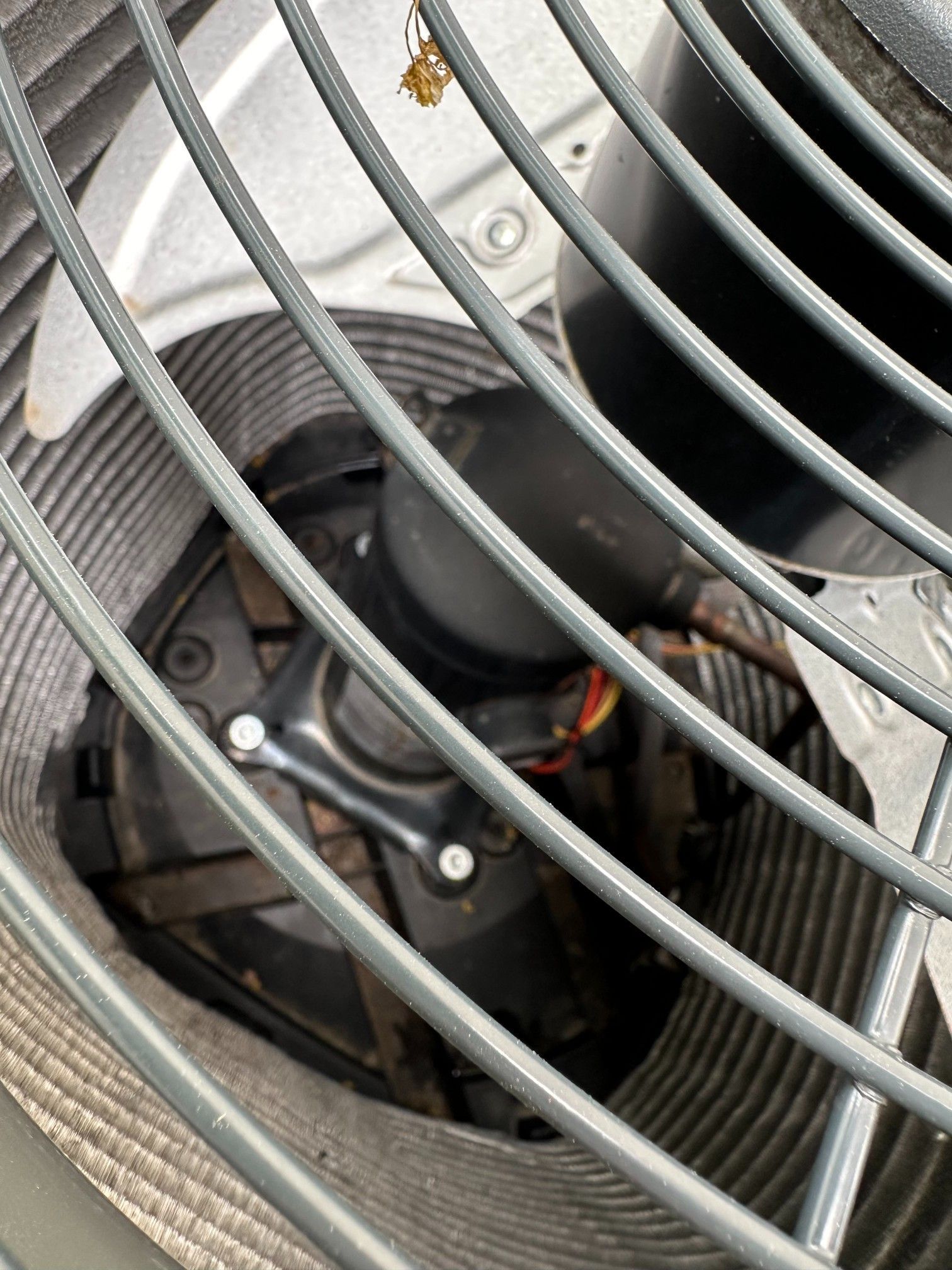 Air conditioner fan motor behind a protective metal grille.