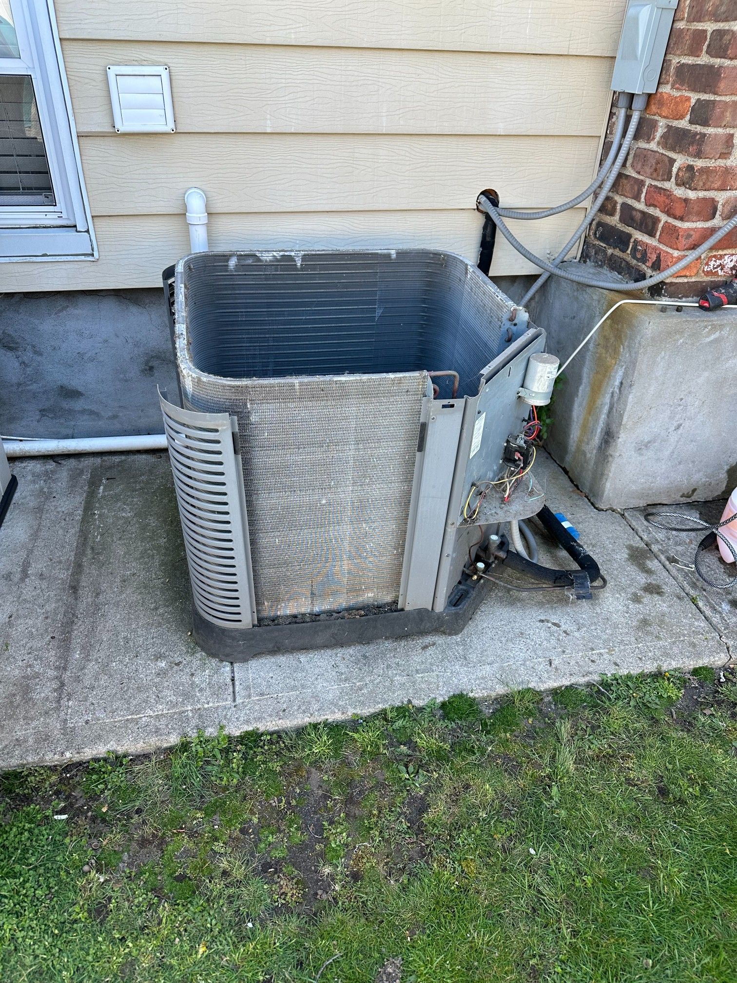 Exterior AC unit on a concrete slab, dusty with exposed internal components.