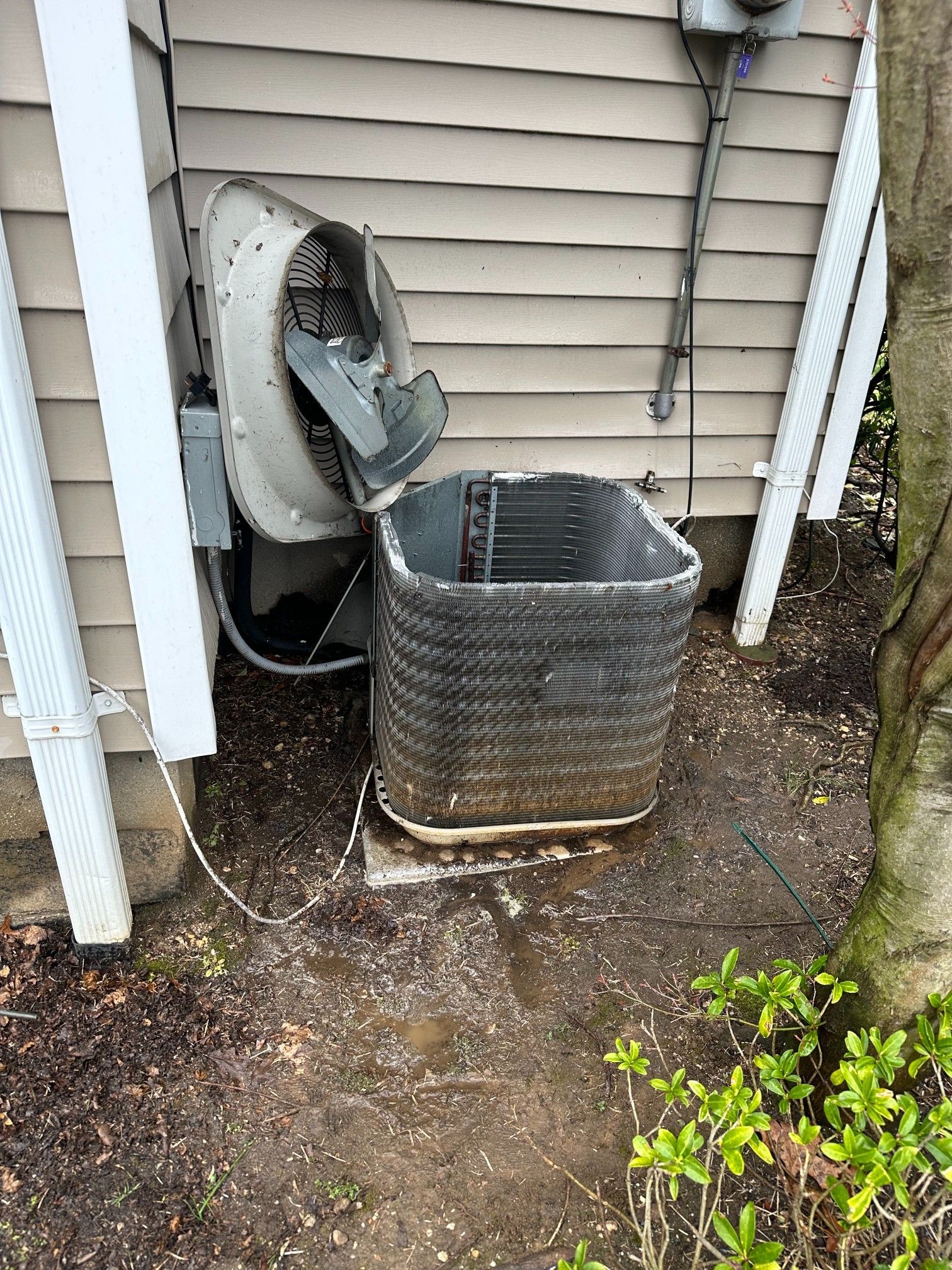 HVAC unit being serviced outdoors with connected gauges and a vacuum pump.