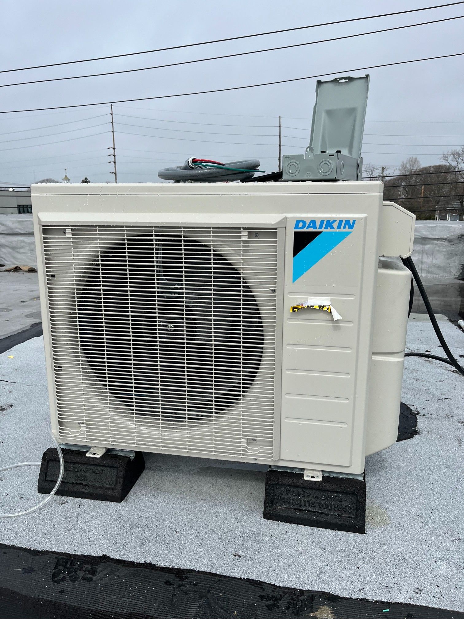 Two HVAC technicians by a brick wall and air conditioner, one with a thumbs up, holding a toolbox.