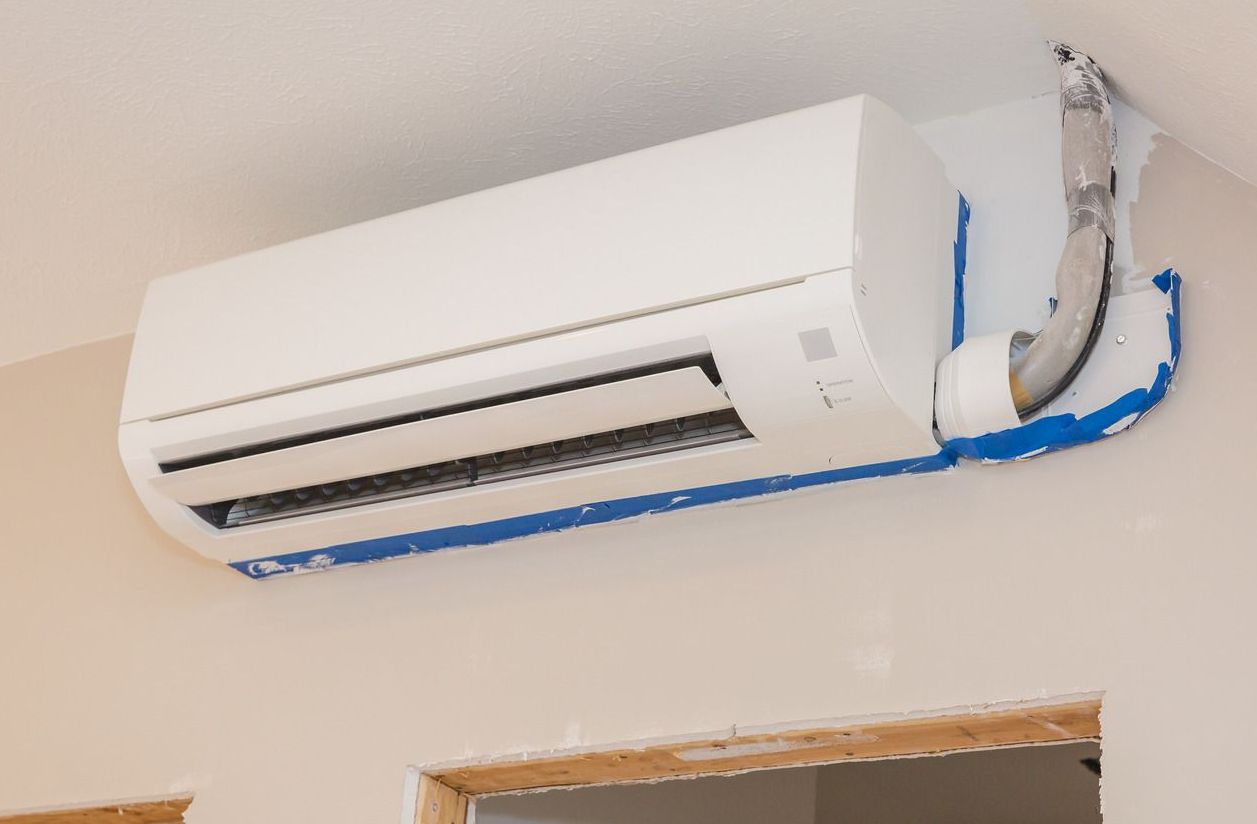 A white air conditioner is hanging on a wall in a room.