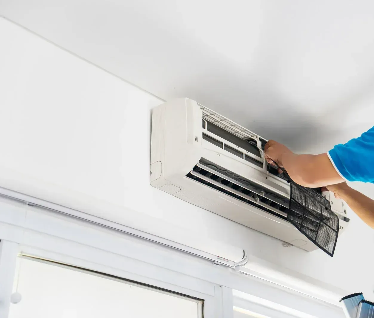 A person is cleaning an air conditioner in a room.