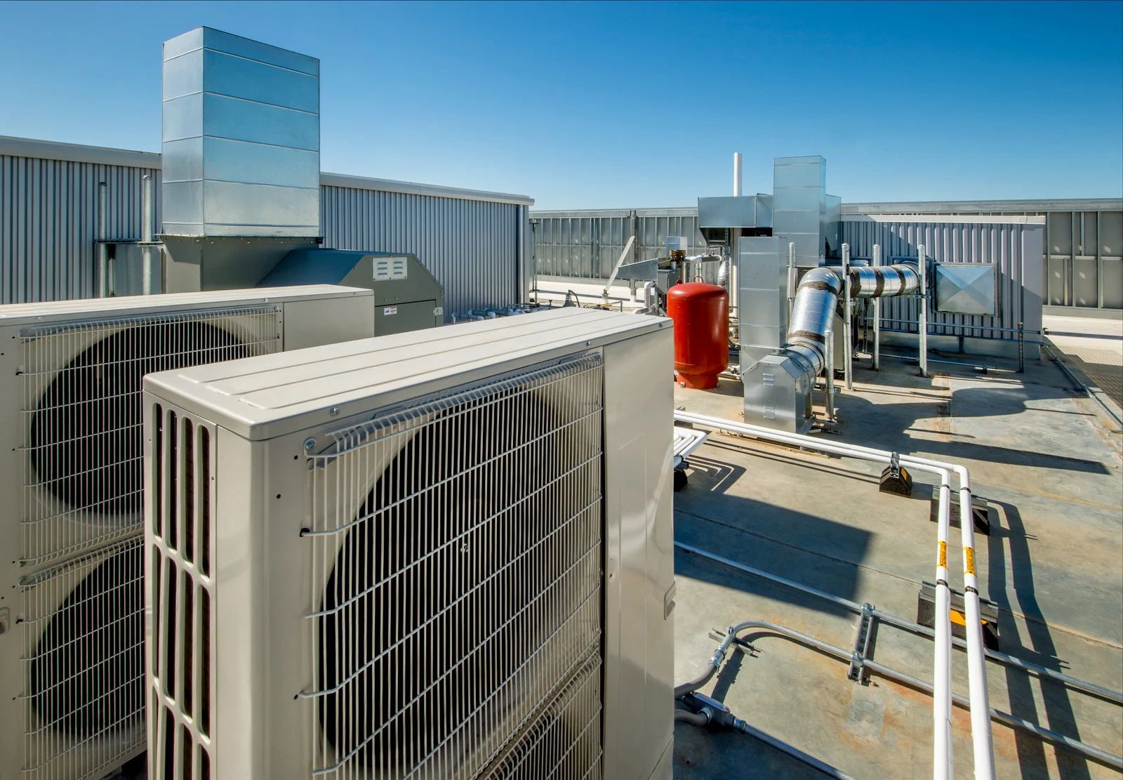 HVAC units and ductwork on a rooftop under a clear blue sky.