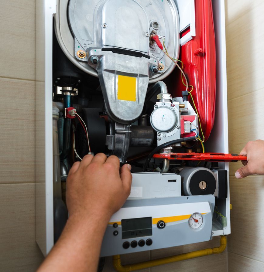 A person is working on a boiler with a wrench