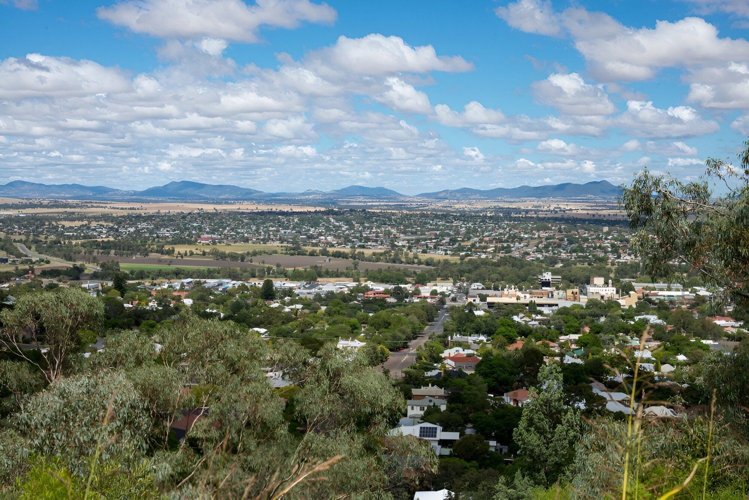 Overlooking a Sprawling Town Under a Blue Sky with Puffy Clouds. Buildings and Trees Stretch to Distant, Hazy Mountains  — Ballimore Welding in Tamworth, NSW