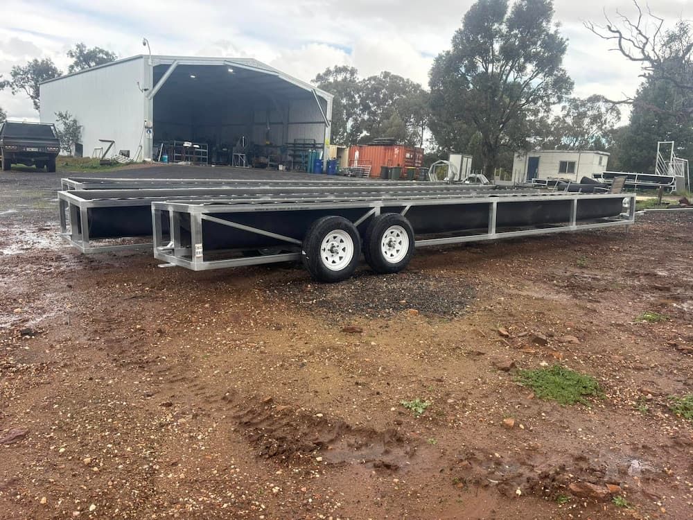 A Long Trailer is Parked in a Dirt Field in Front of a Building — Ballimore Welding in Ballimore, NSW