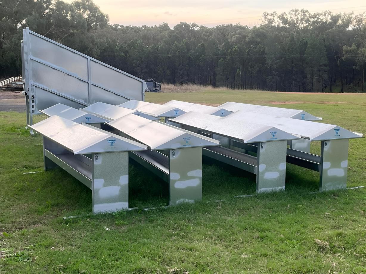 Metal solar panel array on green grass with trees in the background.
