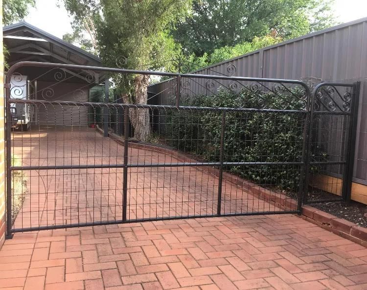 A Black Gate Is Sitting on A Brick Driveway Next to A Fence — Ballimore Welding in Ballimore, NSW