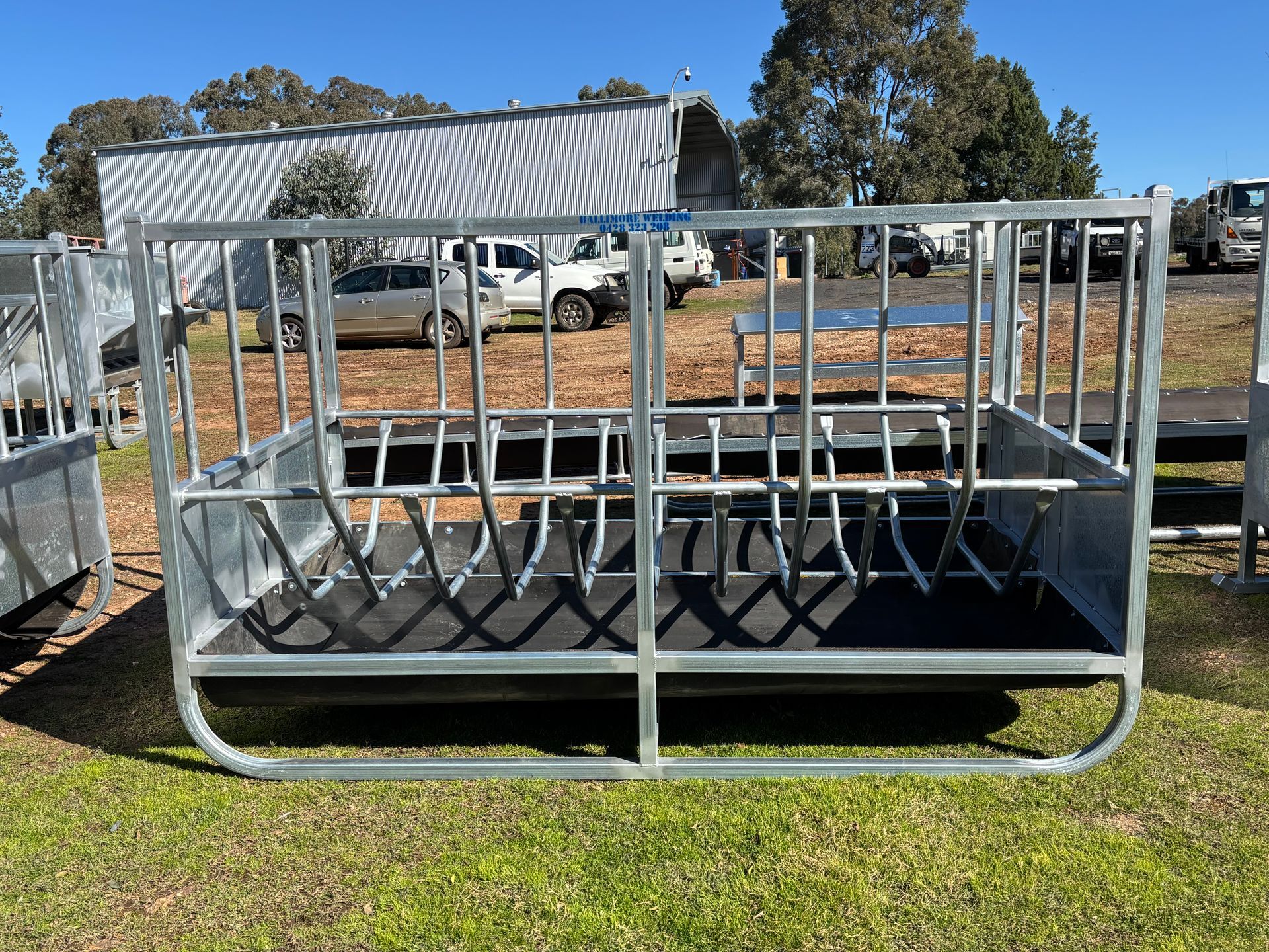 Metal livestock feeder, rectangular, with vertical bars and interior feeding area.