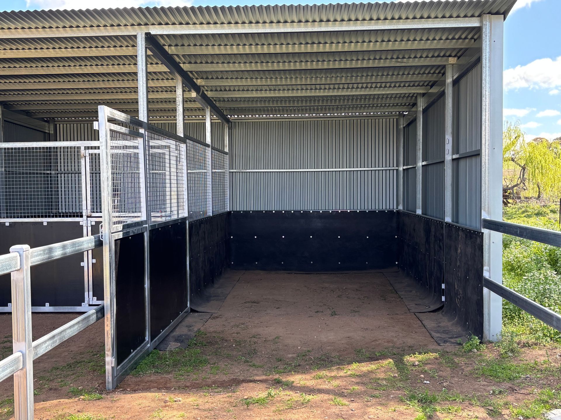 A Dirt Field with A Black Fence and Trees in The Background — Ballimore Welding in Ballimore, NSW