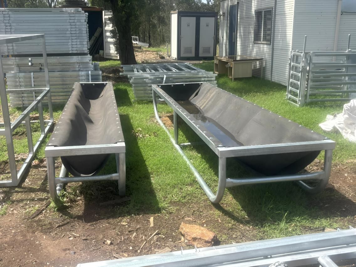 Two Metal Troughs Are Sitting on Top of A Lush Green Field — Ballimore Welding in Orange, NSW