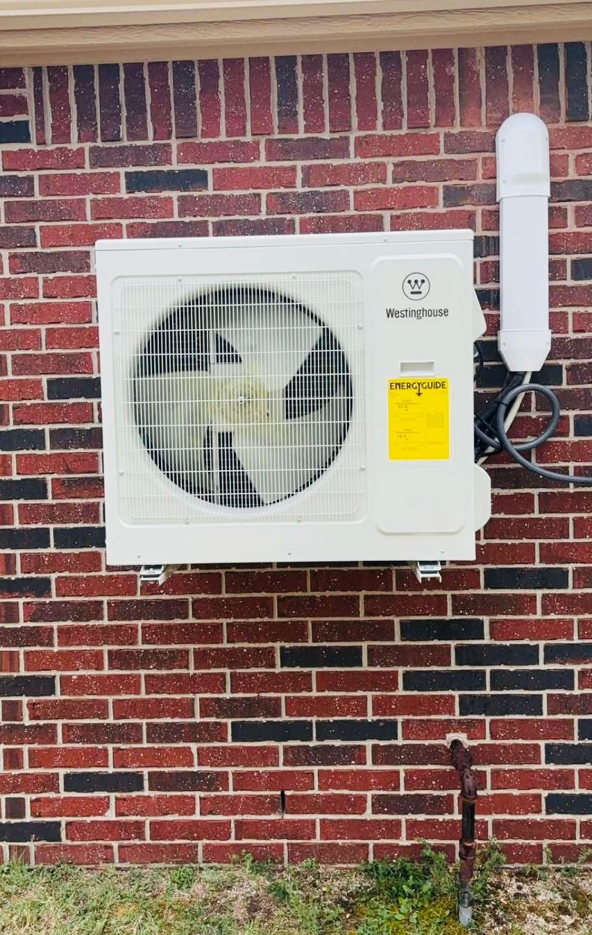 A white air conditioner is mounted on a brick wall