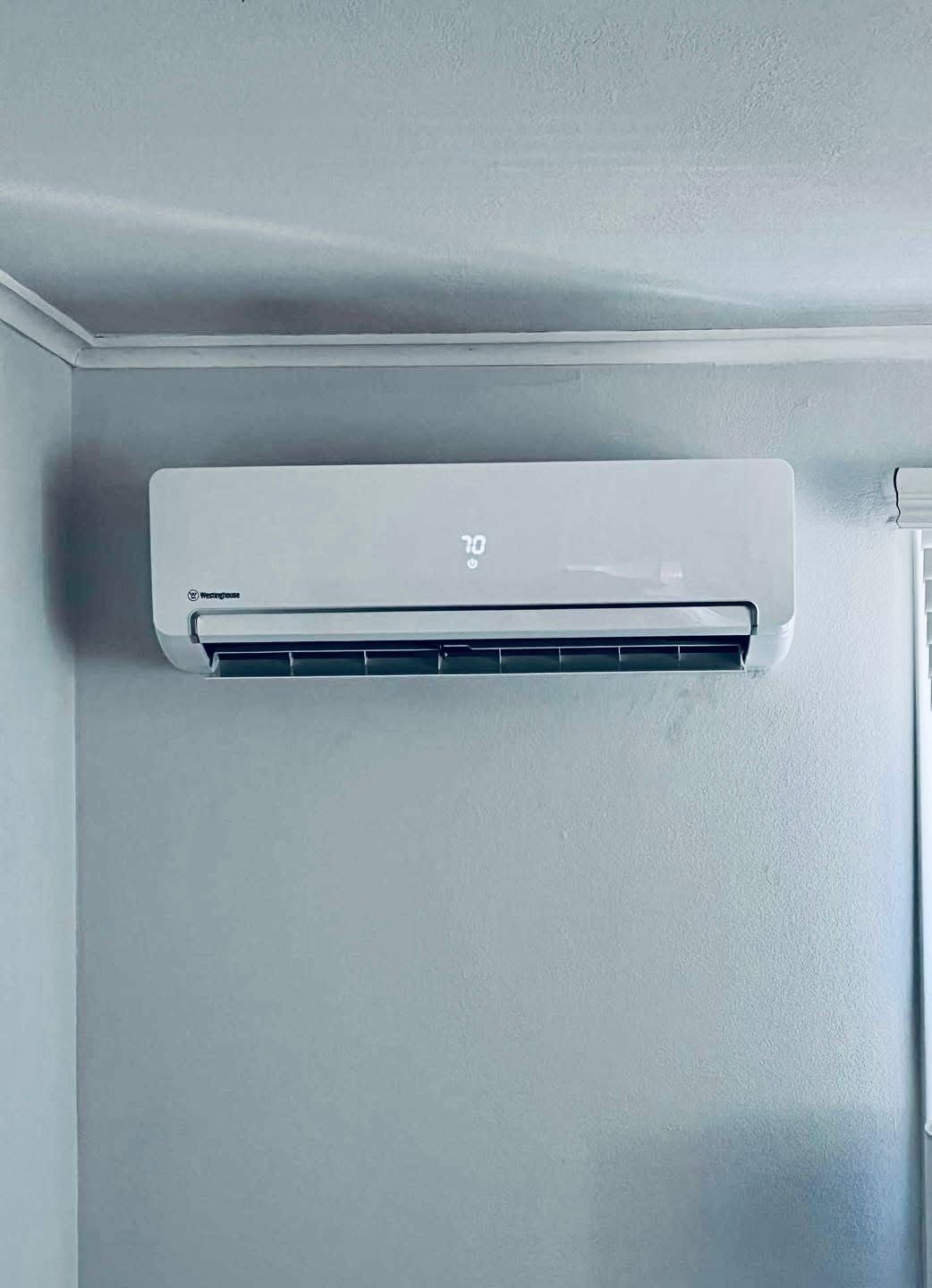 A white air conditioner is hanging on a wall in a room.
