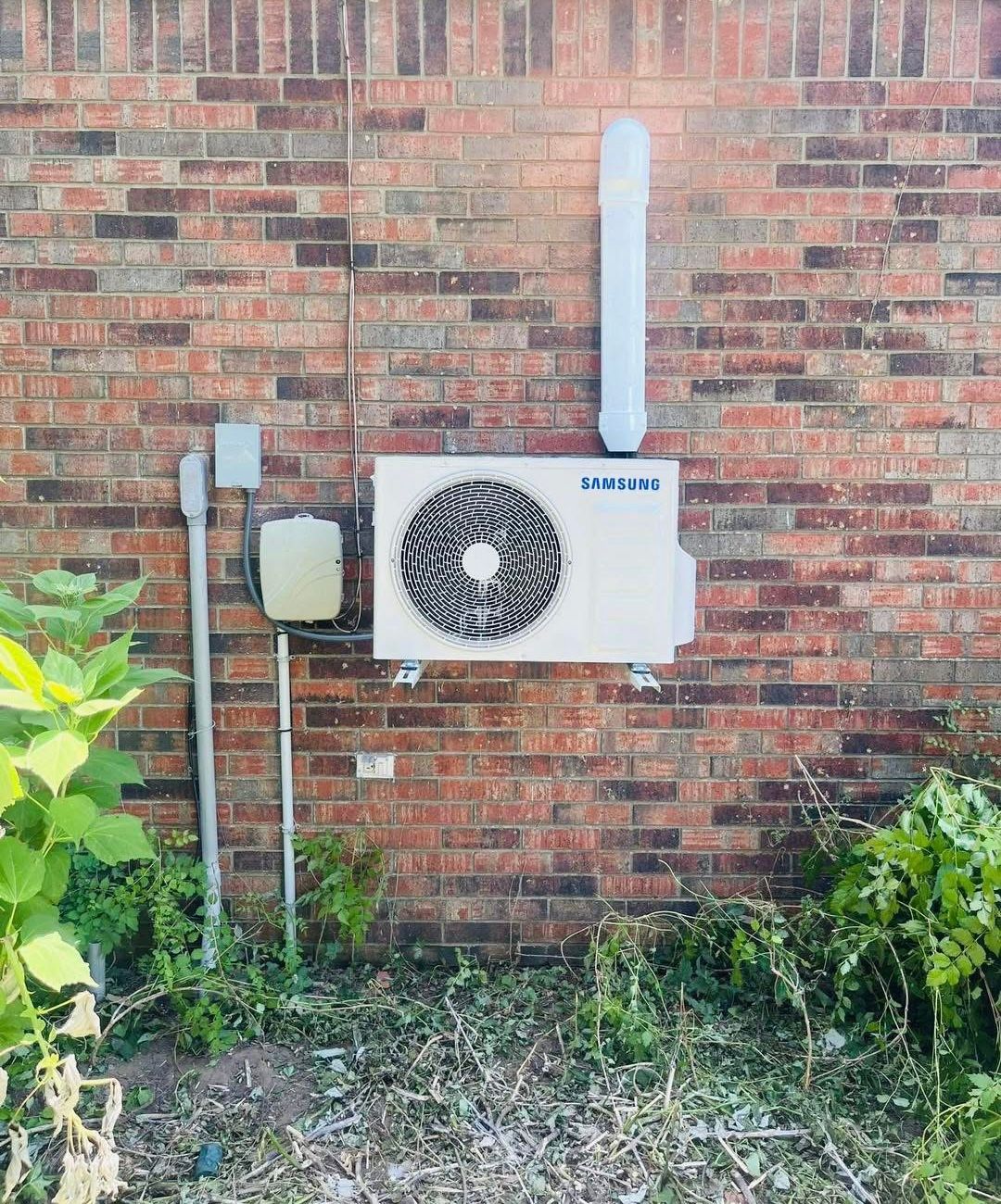 A samsung air conditioner is mounted on the side of a brick building.