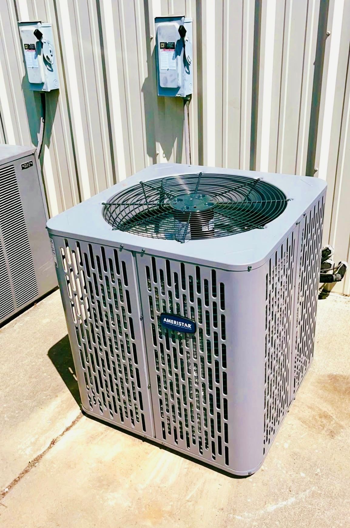 An air conditioner is sitting on the sidewalk in front of a building.