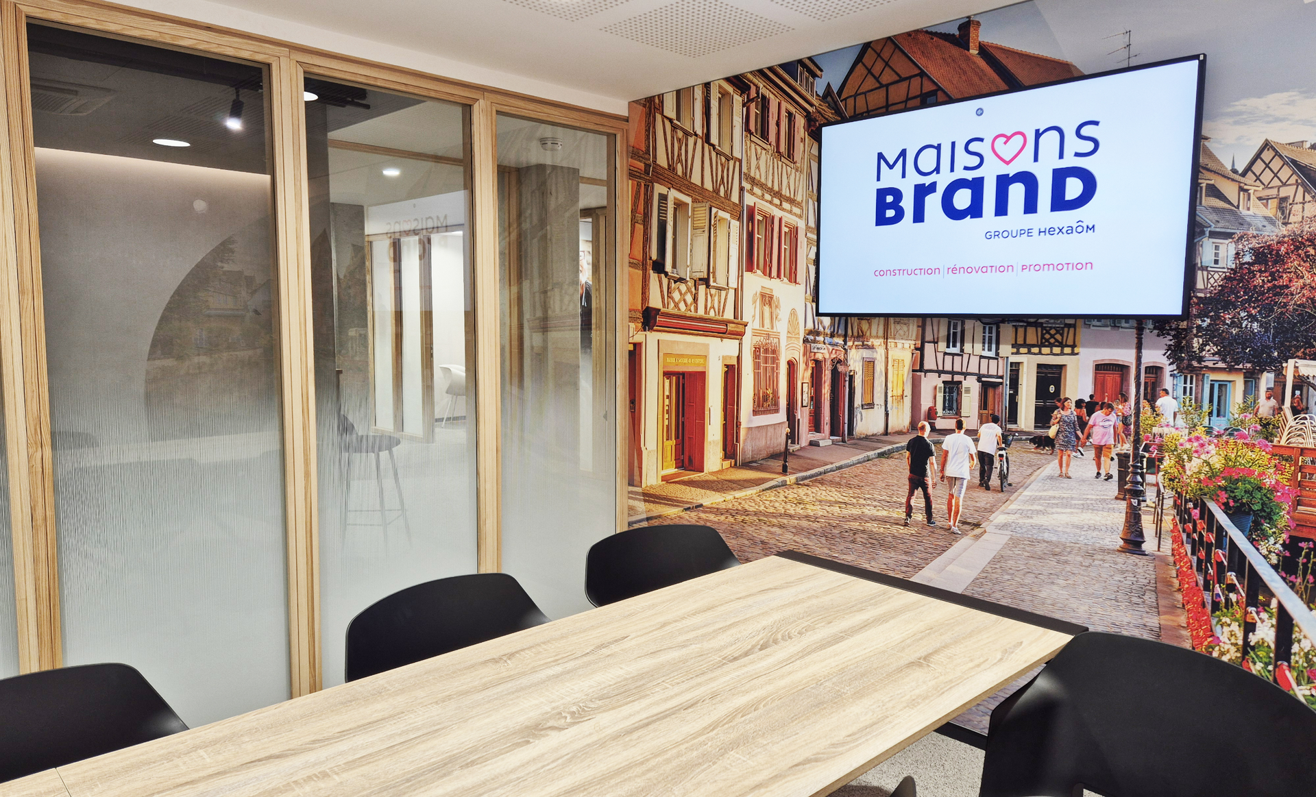 Salle de conférence avec une table, des chaises, un écran de télévision et une fresque d'une ville européenne.
