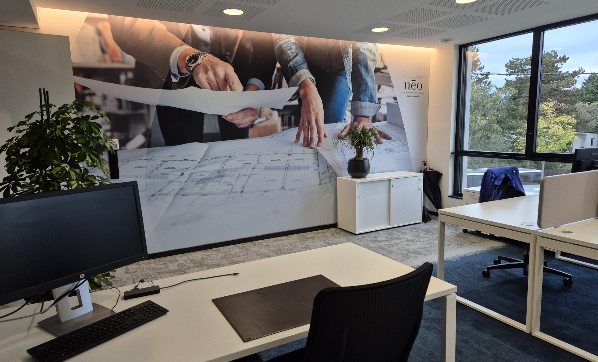 Espace de travail avec bureaux, une grande murale et une fenêtre avec vue extérieure.