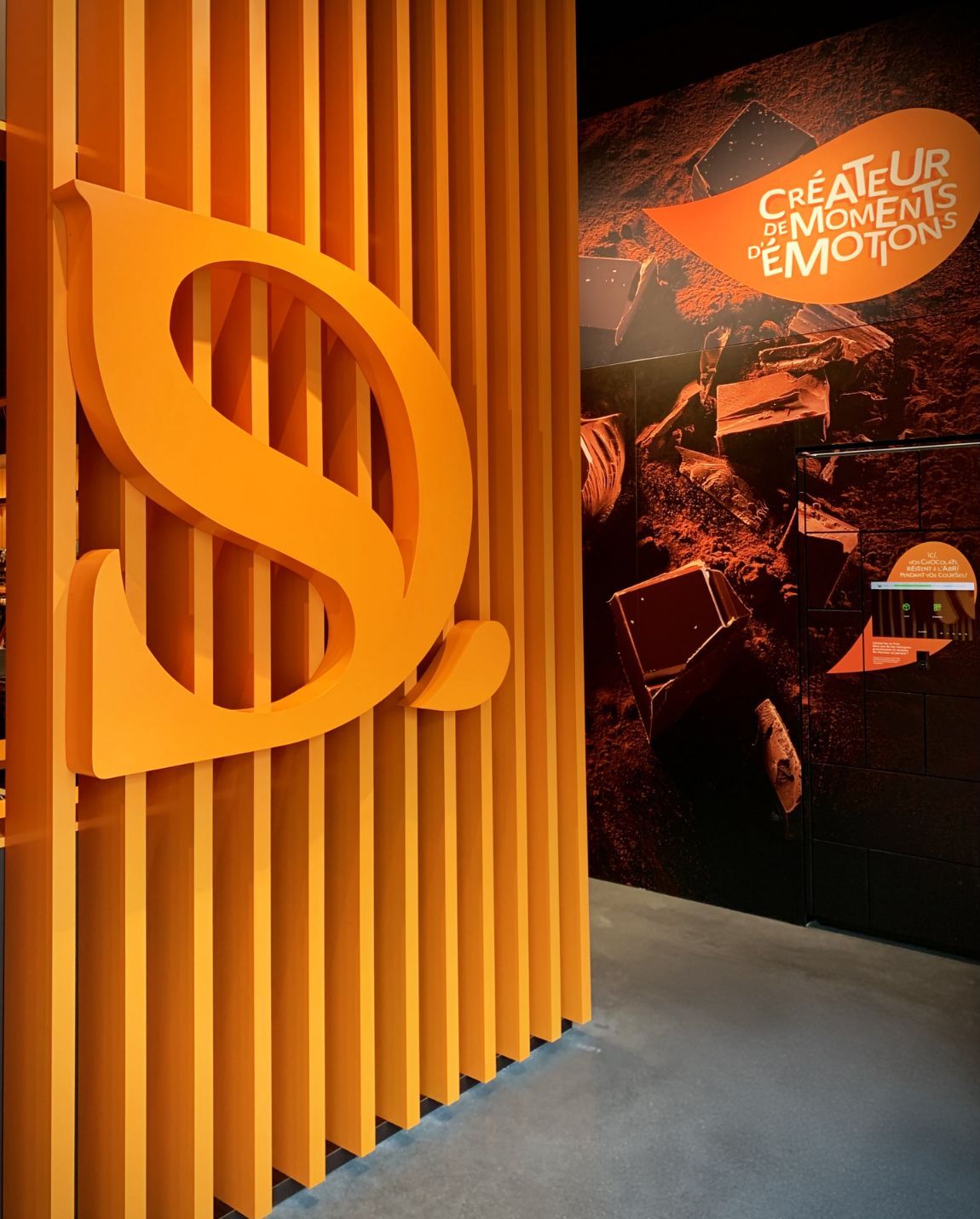 Logo orange avec un « S » à l'intérieur d'une paroi verticale orange. Texte et chocolat en arrière-plan.