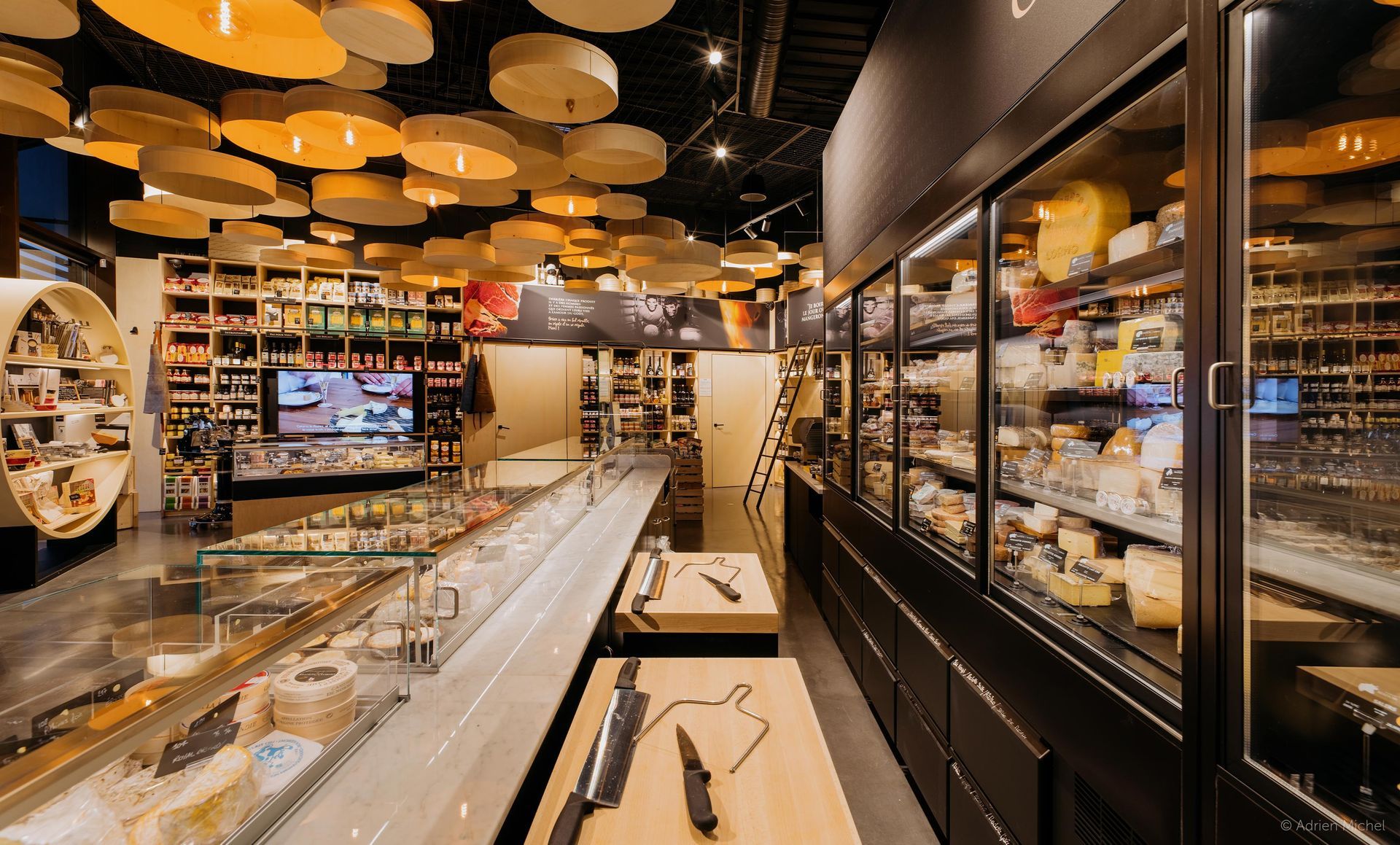 Intérieur d'une boutique gastronomique proposant fromages, vins et charcuterie. 