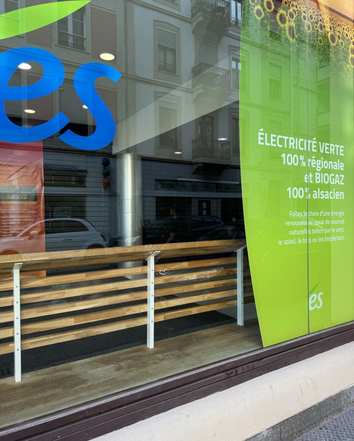 Vitrine ES avec texte vert et bleu, rambarde en bois.