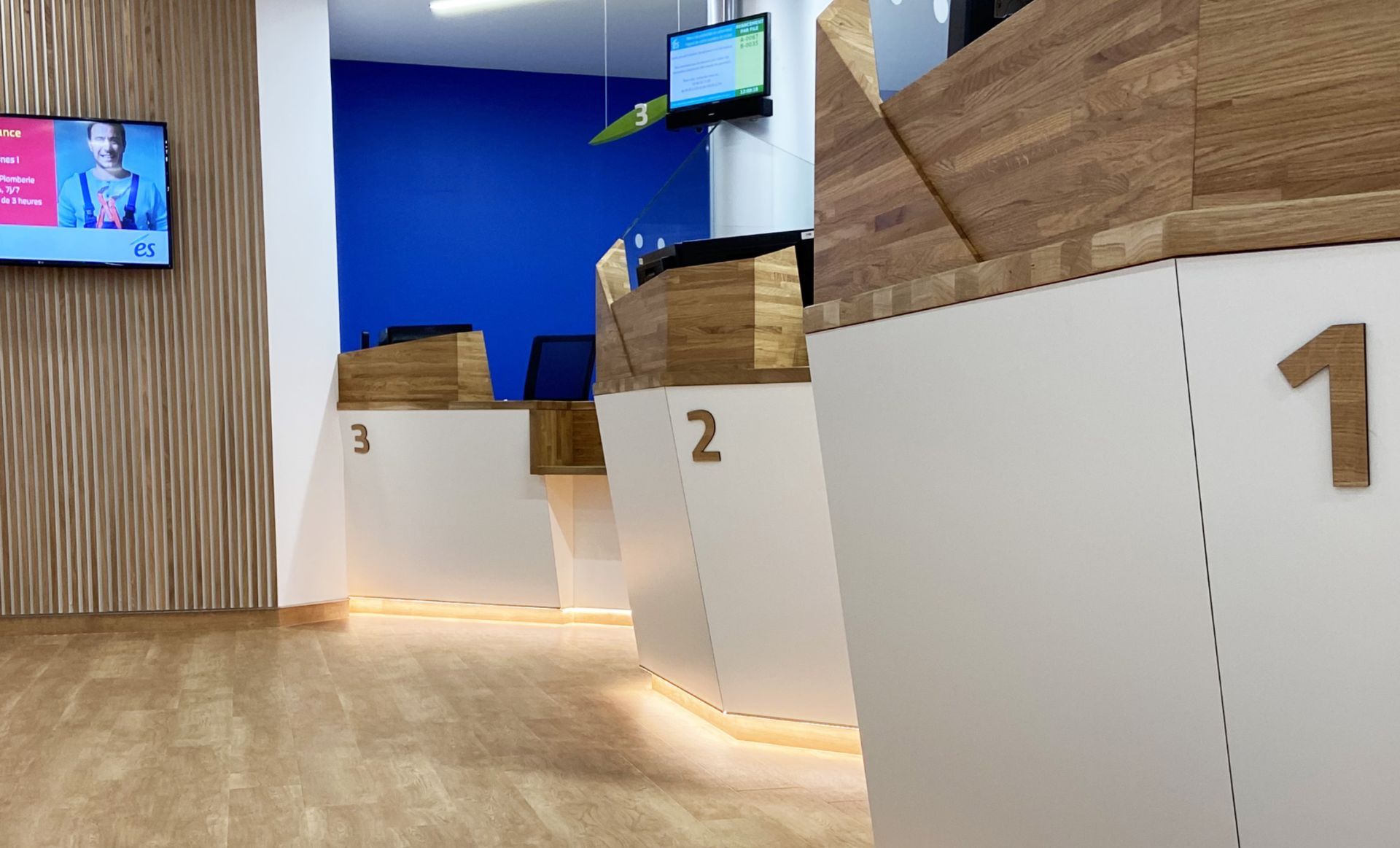 Vue intérieure de trois comptoirs de service à la clientèle numérotés 1, 2 et 3, dans un bureau moderne et lumineux.