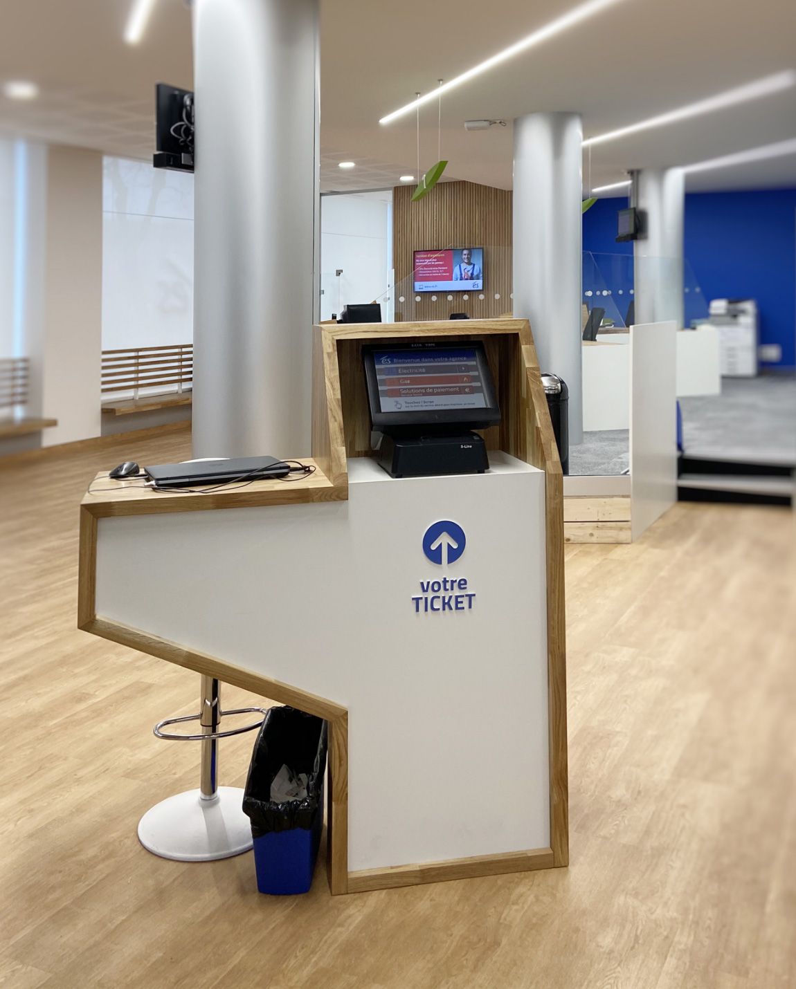 Comptoir d'accueil blanc avec écran, en bois dans un bureau moderne.