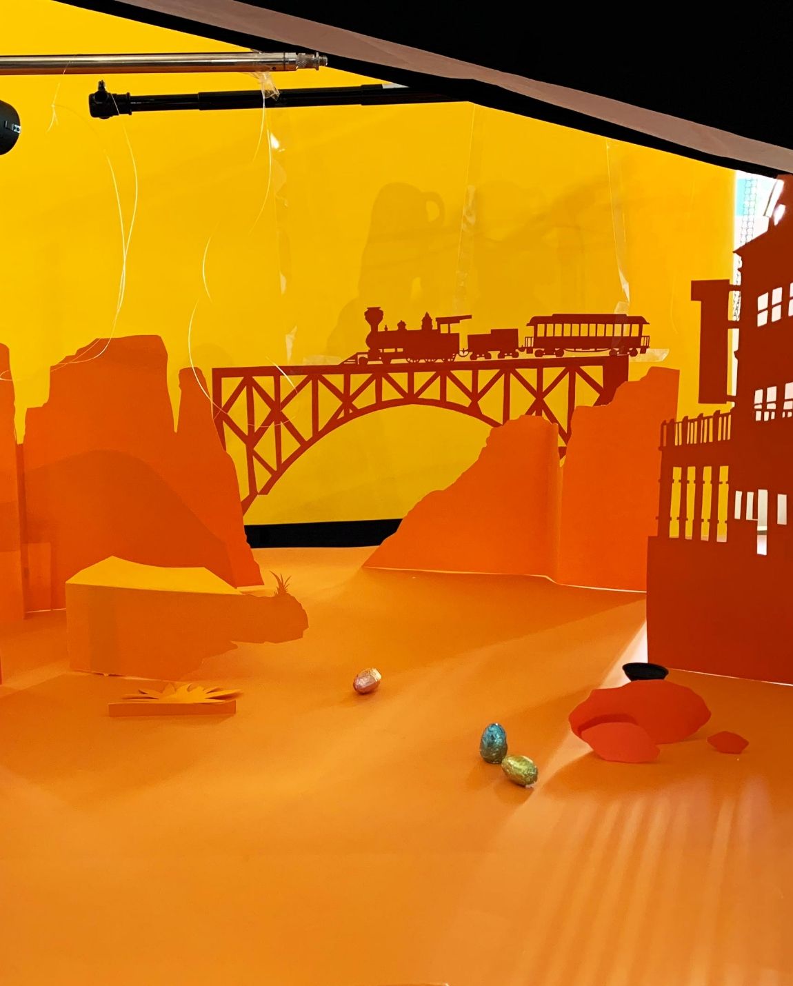 Un diorama aux tons orange d'une scène du Far West : train sur un pont, bâtiments et billes.