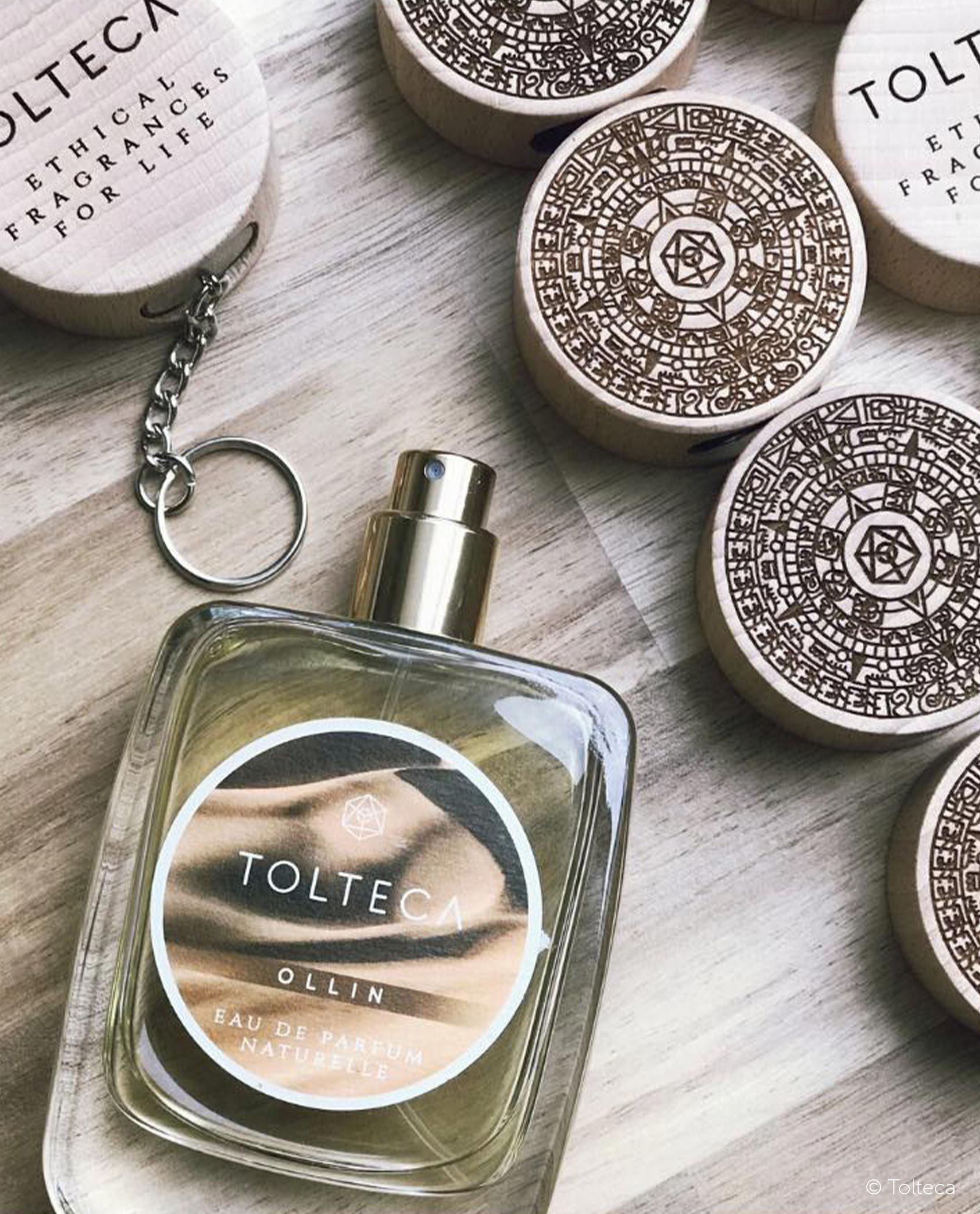 Flacon de parfum avec une étiquette beige à côté de plusieurs bouchons en bois avec des motifs gravés.