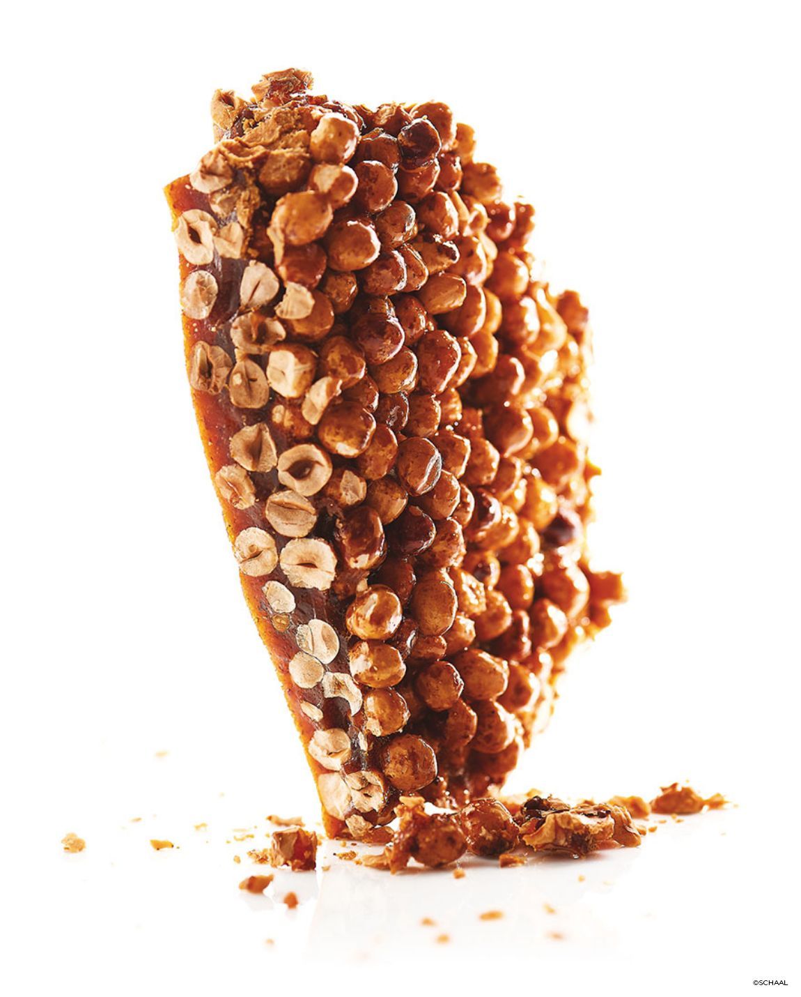 Friandise au caramel et aux noisettes, inclinée, sur fond blanc.