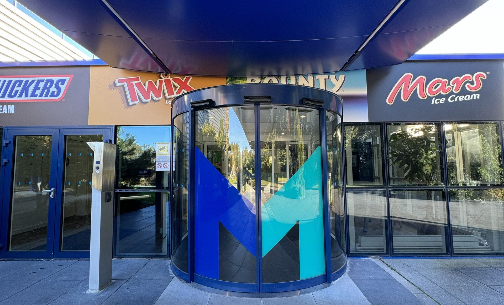 Entrée d'une boutique avec une porte tournante, décorée d'un grand logo 
