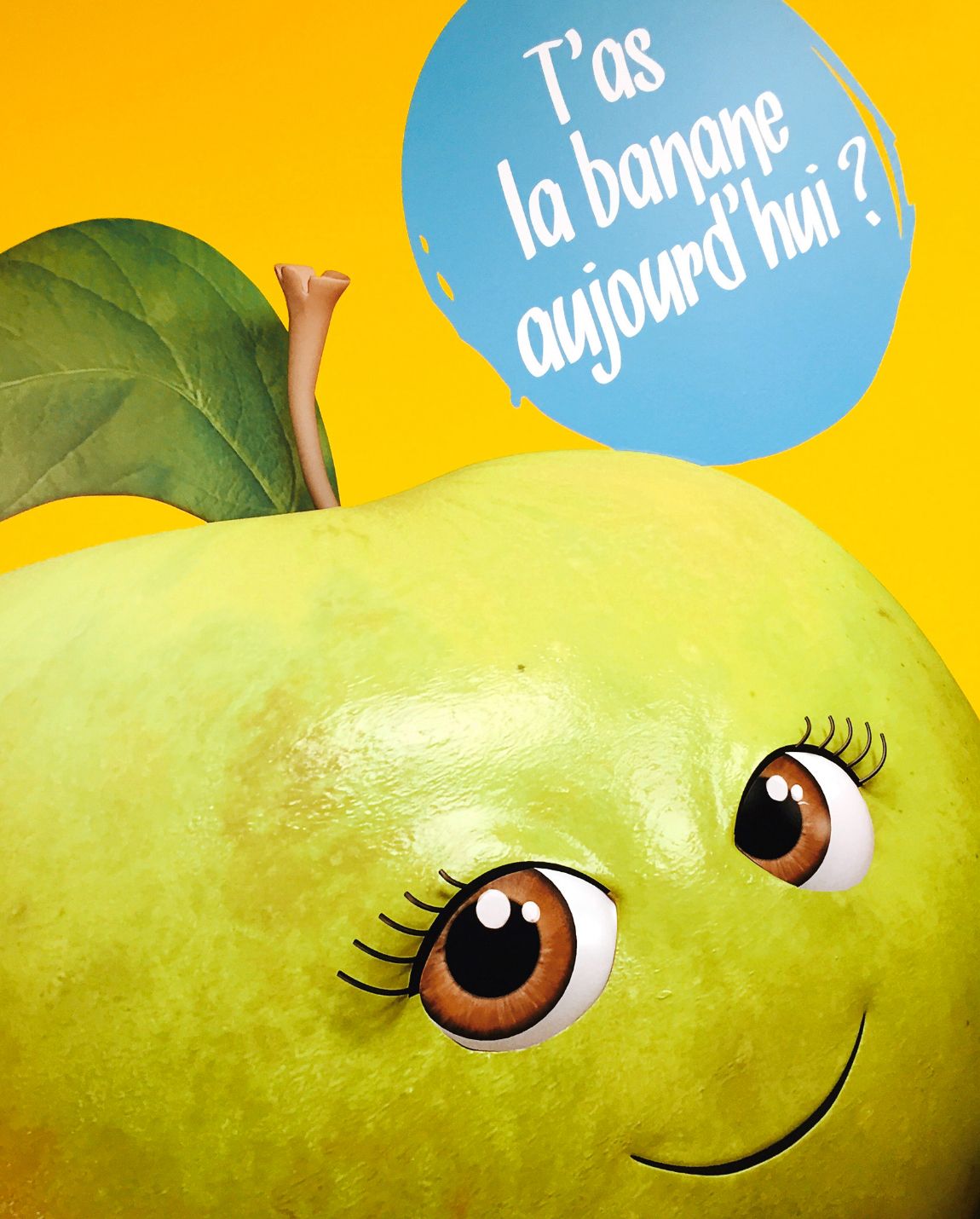 Poire verte avec des yeux et un sourire, tenant une bulle de dialogue bleue. « T'as la banane aujourd'hui ? ».