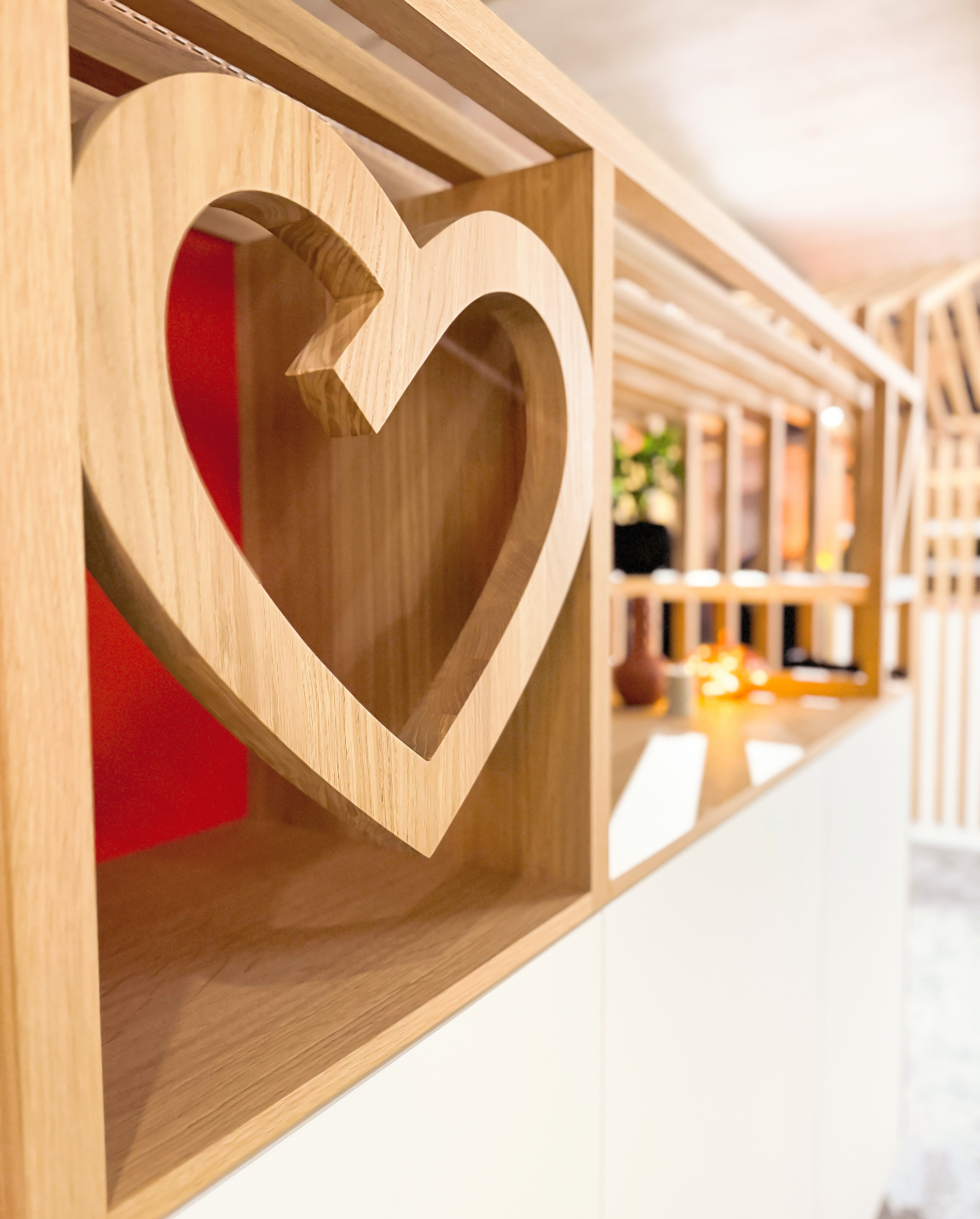 Étagère en bois avec un détail découpé en forme de cœur, armoire blanche en dessous.