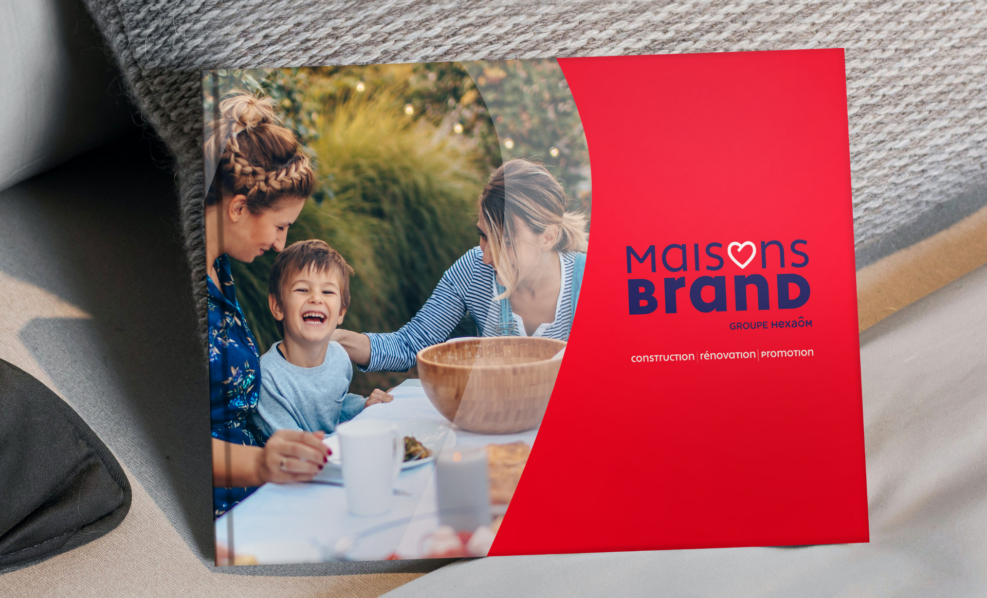 Un livre photo avec une famille à table, couverture rouge avec le logo 