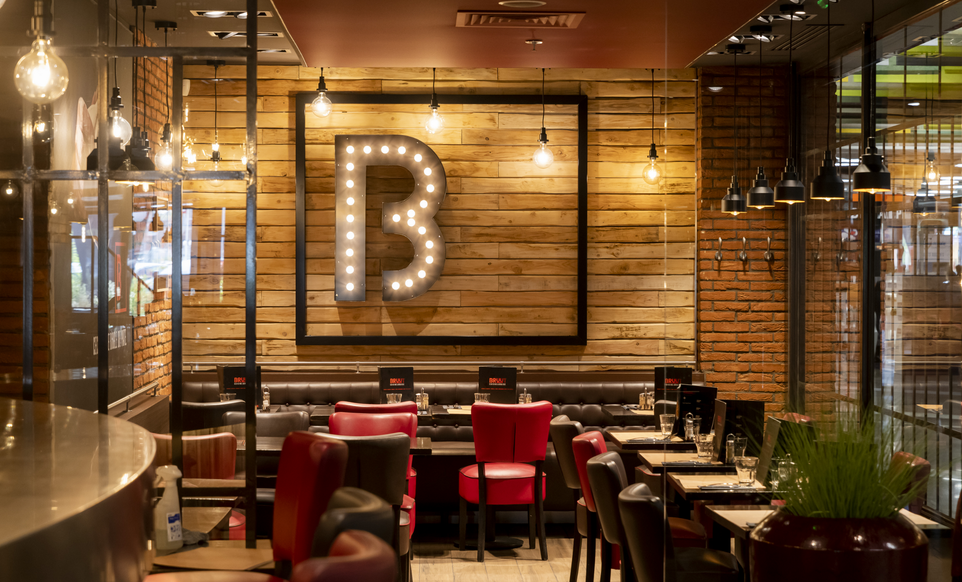 Intérieur du restaurant avec panneau « B » sur un mur en bois, sièges rouges.
