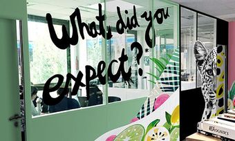 Espace bureau avec paroi vitrée : « À quoi vous attendiez-vous ? » Décor vert et coloré, imprimé fruits et guépard.
