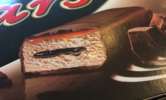 Contenants de crème glacée Snickers et Mars avec des boules de crème glacée arrosées de caramel et de chocolat.