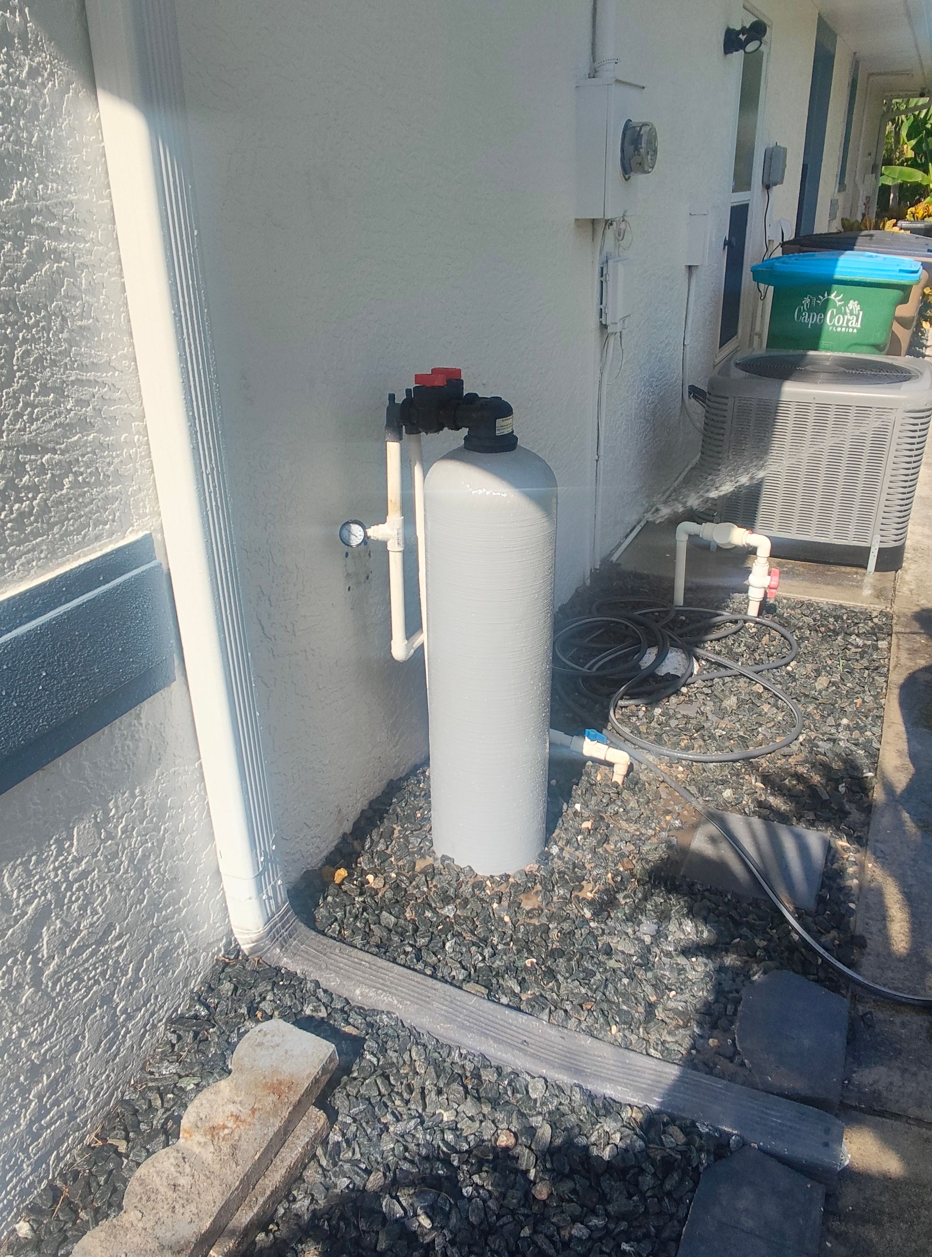 A person is cleaning a water filter next to a water tank.