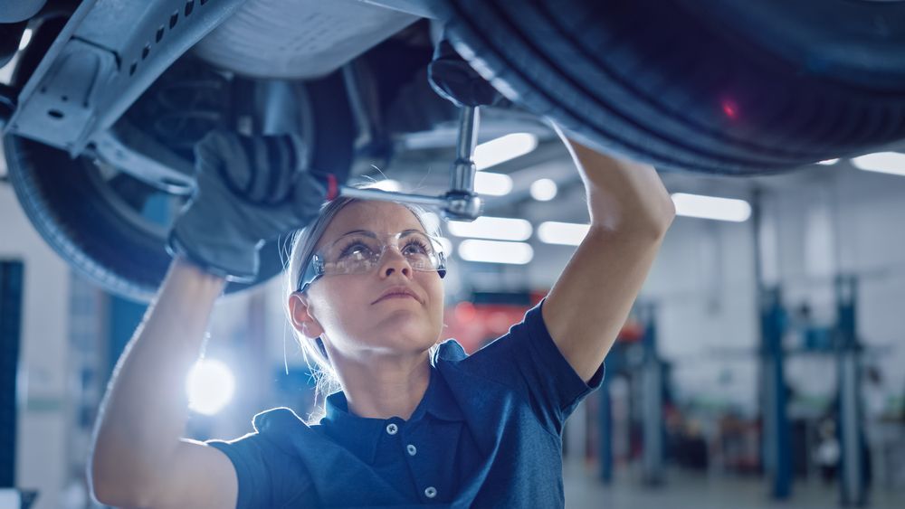 A Woman Is Working On The Underside Of A Car In A Garage — MB Automotive In Garbutt, QLD